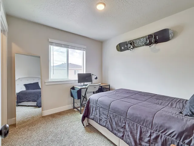 Bedroom with carpet flooring, a textured ceiling, and an office area