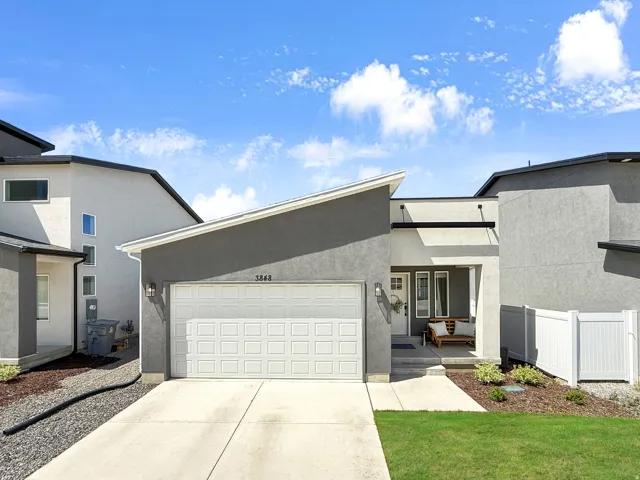 View of front of home with stucco siding, a garage, driveway, and covered porch