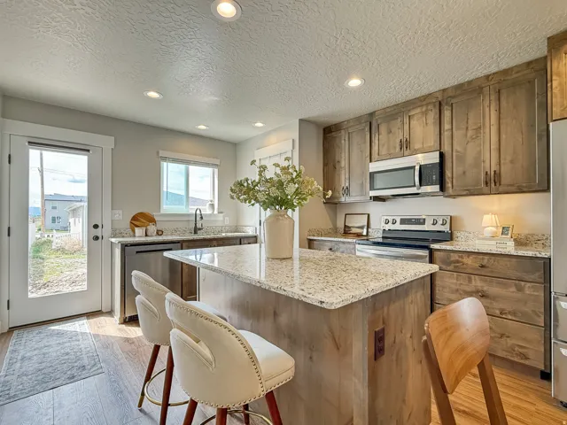 Kitchen featuring recessed lighting, stainless steel appliances, a center island, light stone countertops, and a textured ceiling