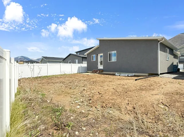 Rear view of property with entry steps, stucco siding, and a fenced backyard