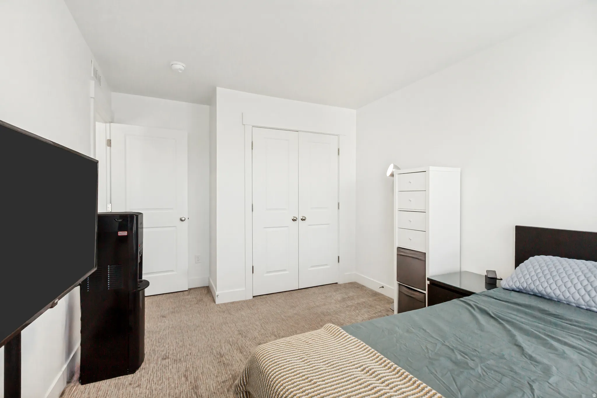 Bedroom featuring light colored carpet and a closet.