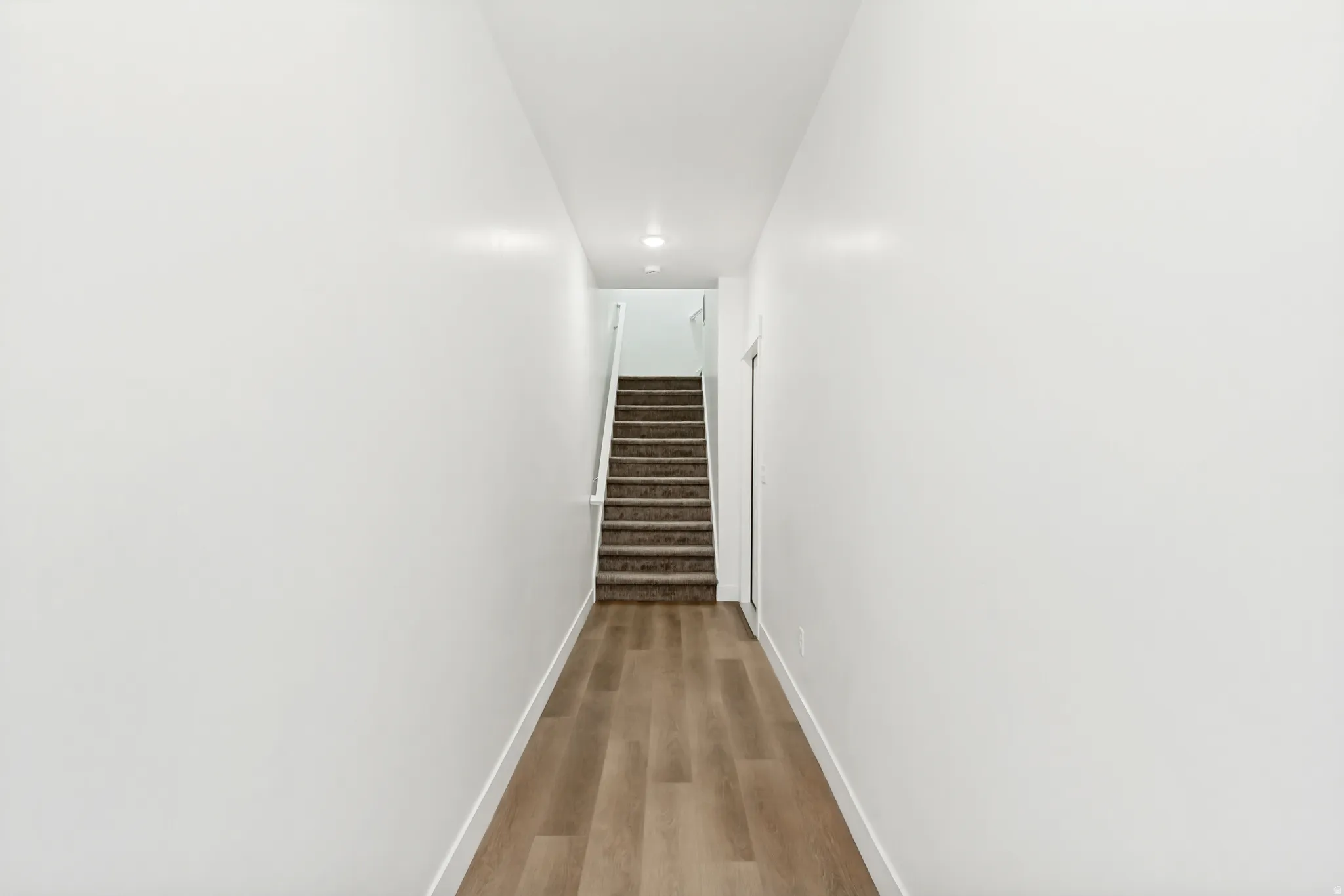 Corridor featuring baseboards and light wood finished floors.