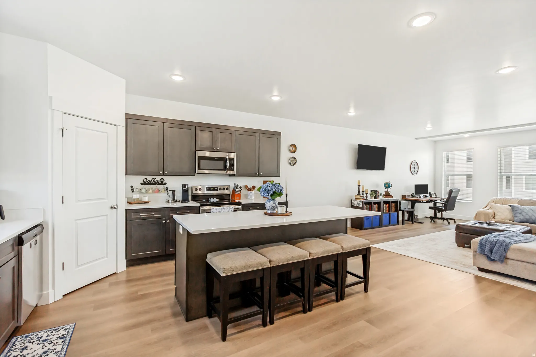 Kitchen featuring open floor plan, light wood finished floors, a center island, dark wood finish cabinets, and a kitchen breakfast bar.