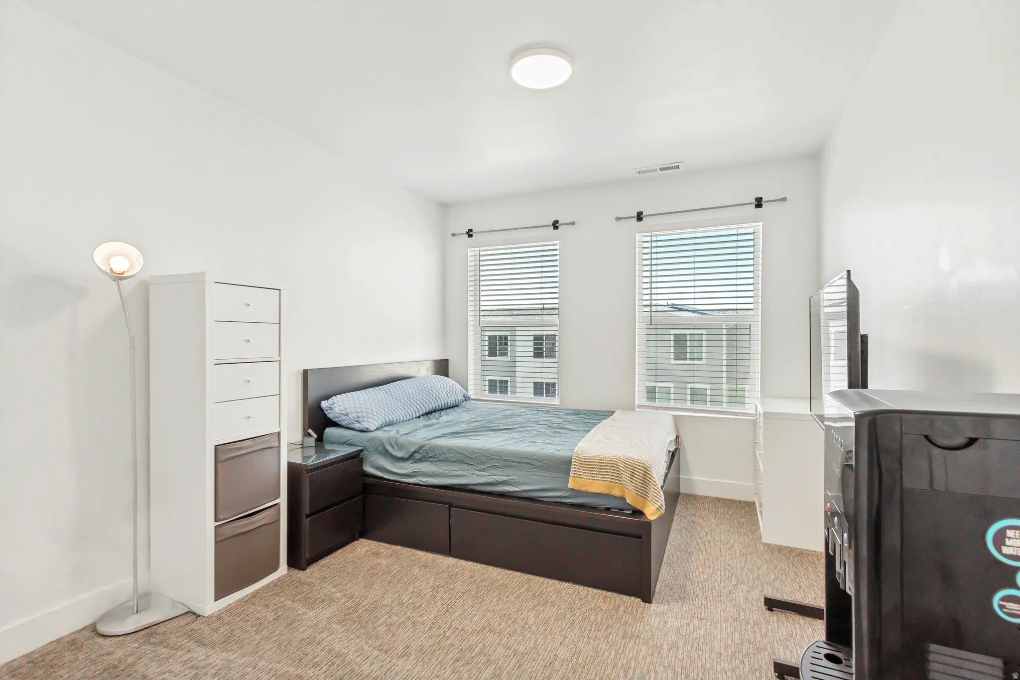 Bedroom with light colored carpet and large windows.