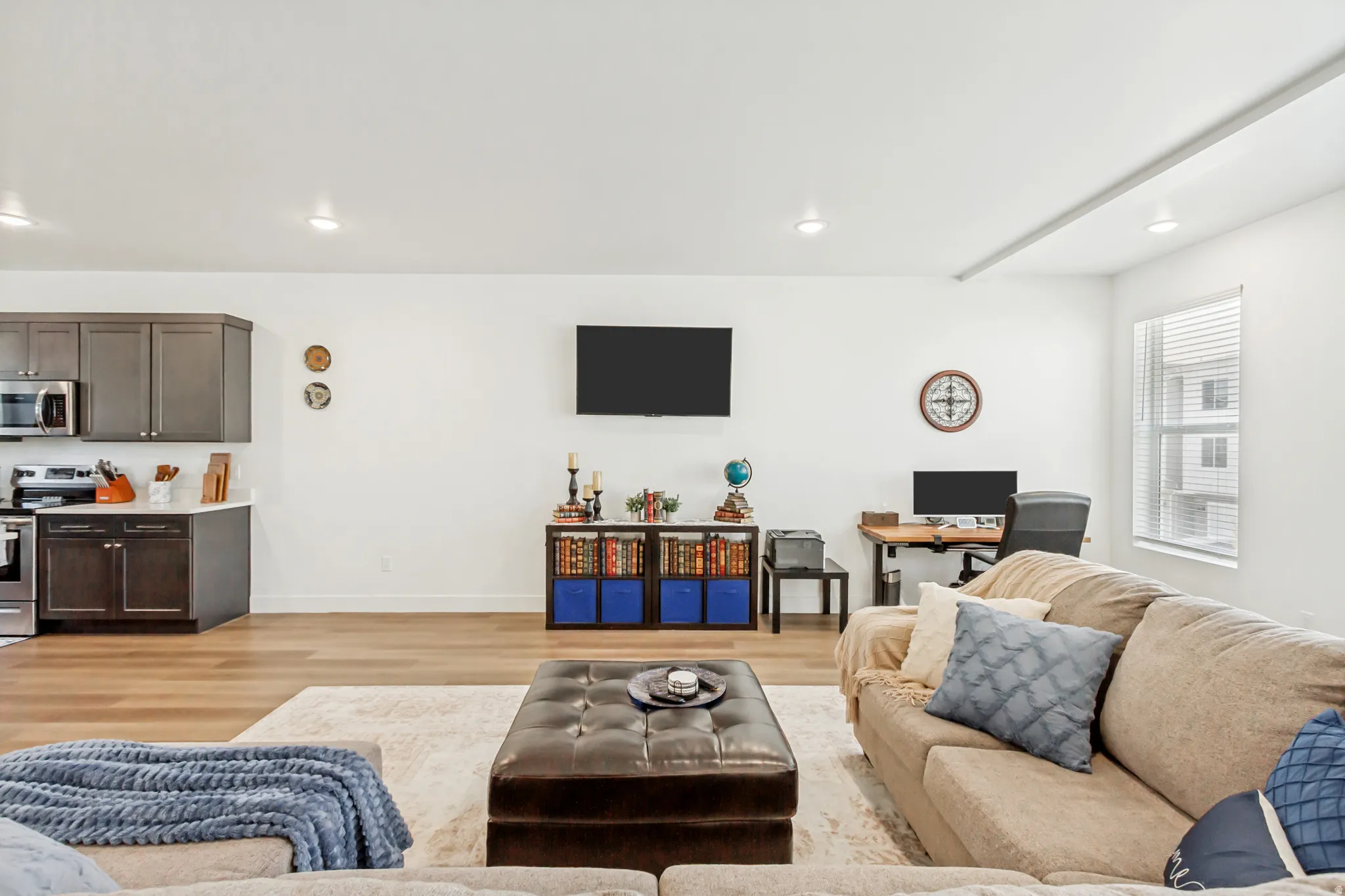Living area with light wood-style floors, and recessed lighting.