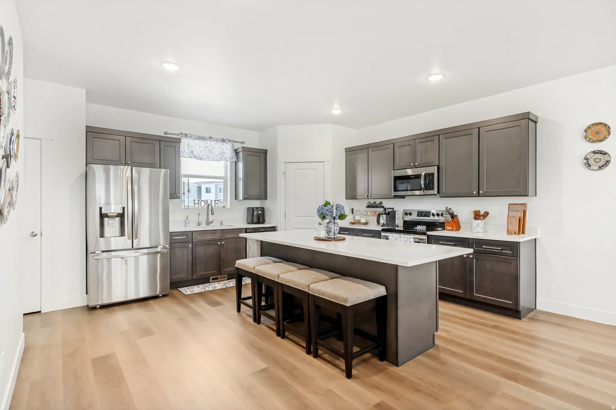 Kitchen with stainless steel appliances, a kitchen bar, dark wood finish cabinets, a kitchen island, and light wood-style flooring.
