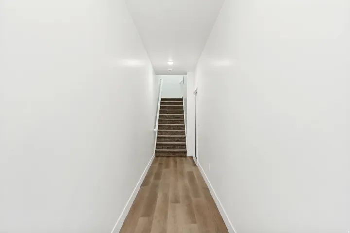 Corridor featuring baseboards and light wood finished floors.
