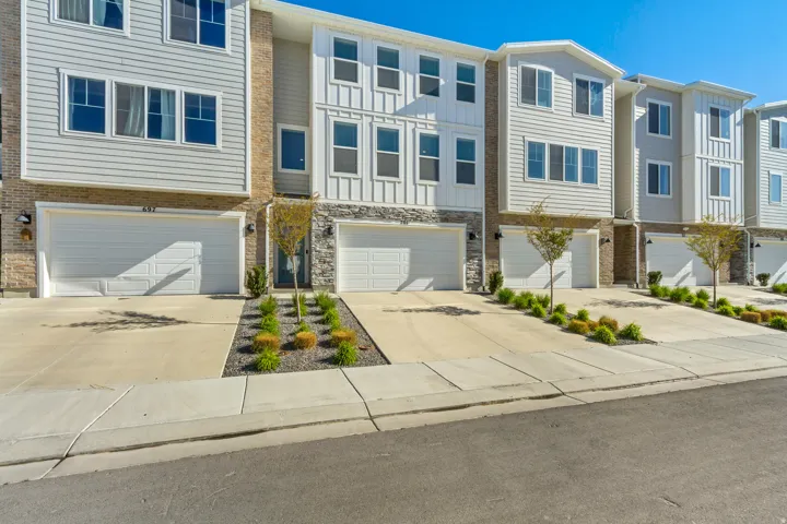 View of front of home featuring concrete driveway and an attached garage.
