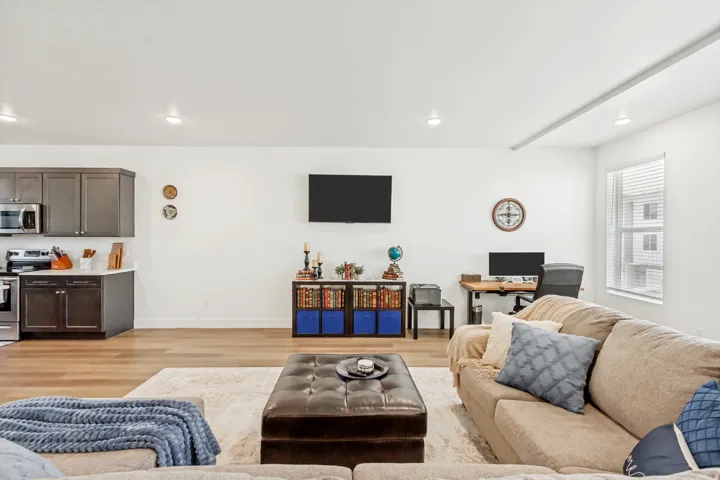 Living area with light wood-style floors, and recessed lighting.