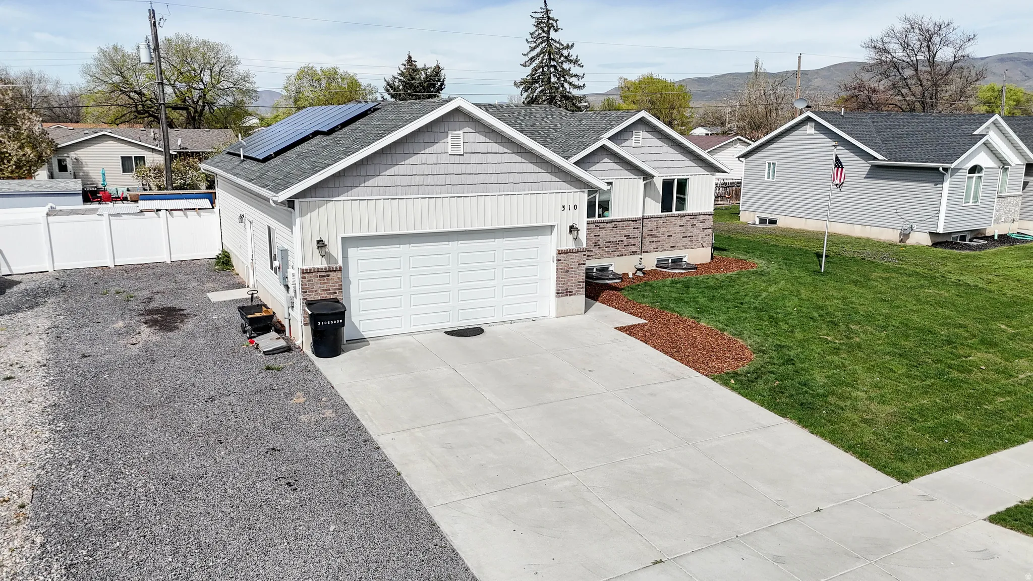 Ranch-style home with solar panels, driveway, board and batten siding, brick siding, and an attached garage