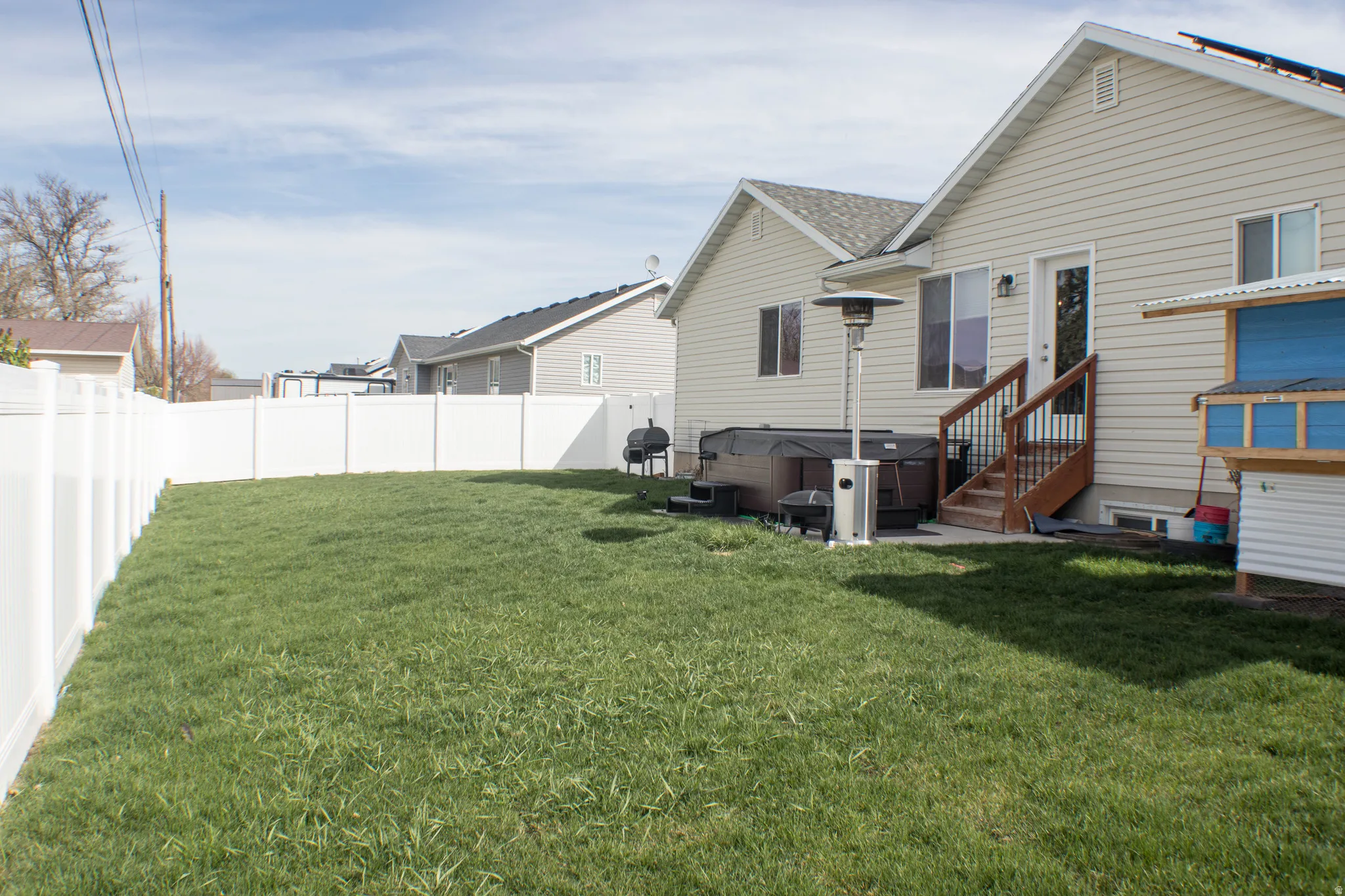 Back of property with a fenced backyard, a hot tub, and a patio area