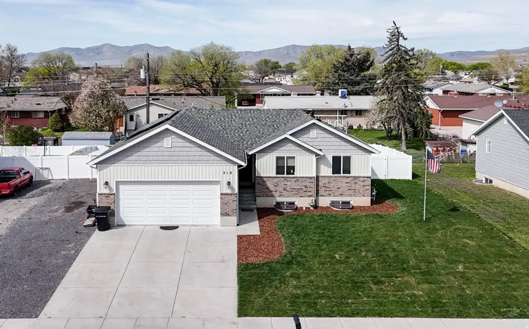 View of front of home featuring board and batten siding, a residential view, driveway, a garage, and a mountain view