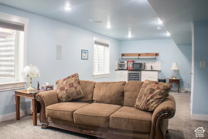 Recessed ceiling lighting, built-in wet bar with cabinetry, beverage cooler, and wall-mounted shelving