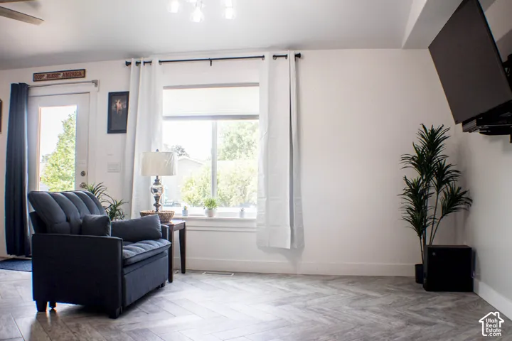 Herringbone-patterned wood-finish flooring, white walls, and a large window with privacy blinds