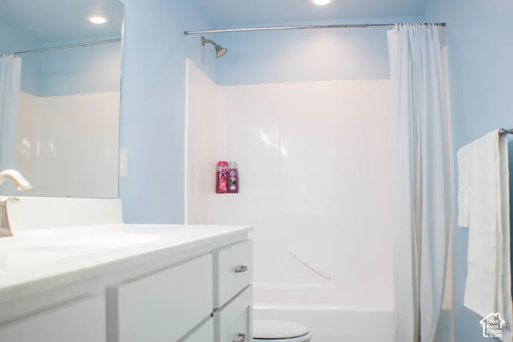 Bathroom featuring a single vanity with storage, a mounted mirror, and a shower-tub combination