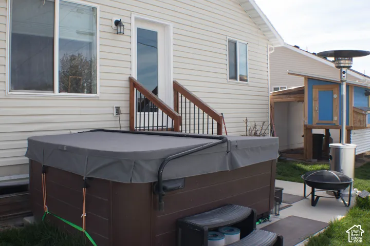Rear view of house featuring a patio, a hot tub, and an outdoor fire pit