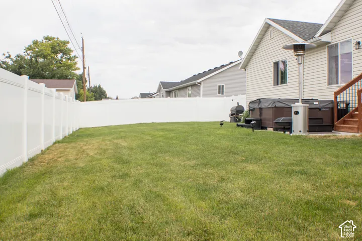 Expansive lawn area with a white vinyl privacy fence and a wooden deck with black metal railings