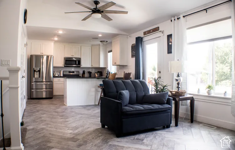 Open-concept living area with herringbone-patterned flooring, recessed lighting, and a ceiling fan