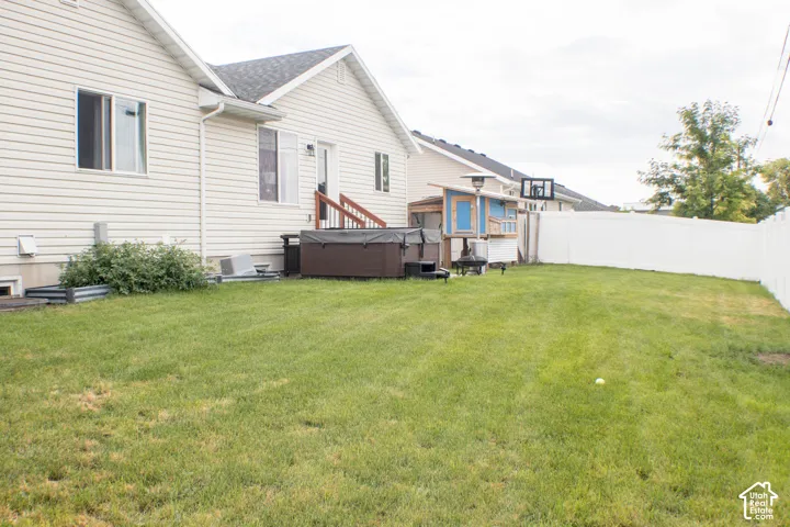 Expansive grassy yard with white vinyl fencing and a covered patio area