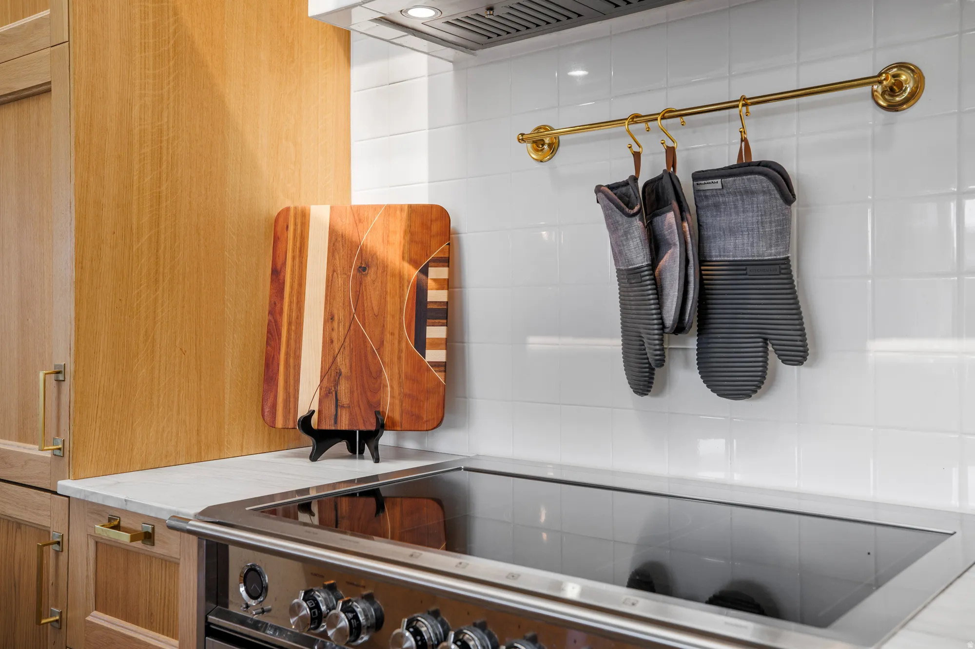 Kitchen view of electric cooktop, custom exhaust hood, and wood finish cabinets