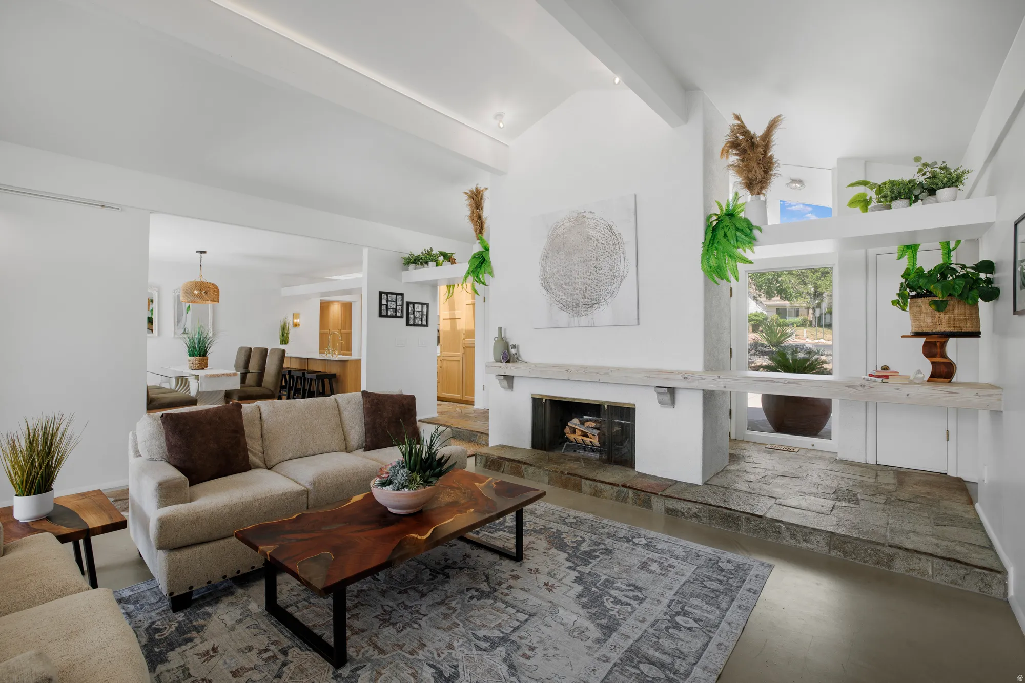 Living room with a fireplace with raised hearth, vaulted ceiling, and wood finished floors