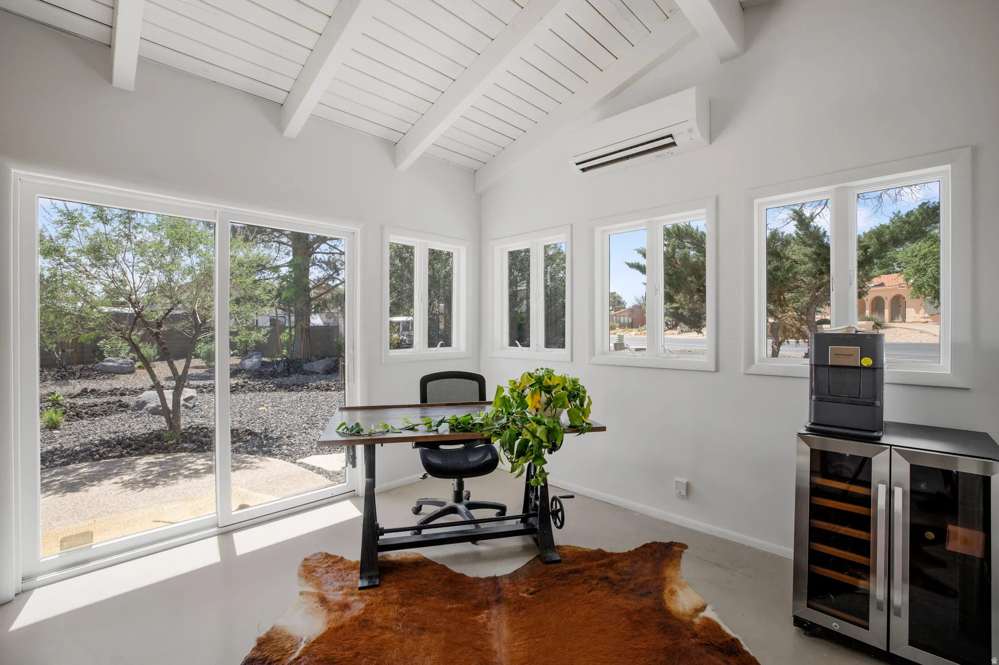 Office with wine cooler, lofted ceiling with beams, and concrete flooring