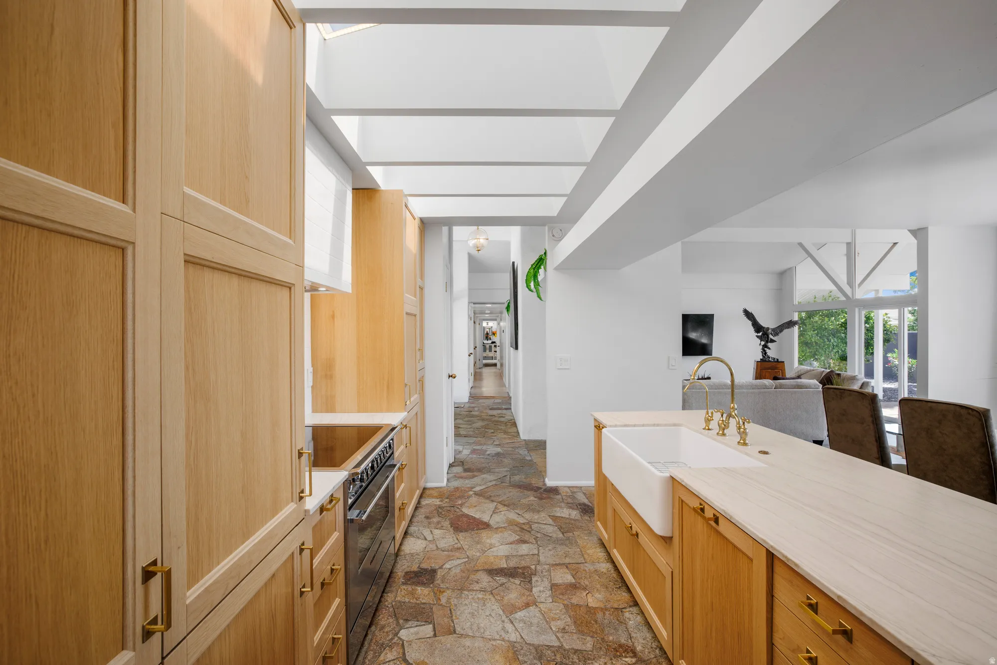 Kitchen featuring light wood finish cabinetry, dark stone finish floors, open floor plan, and stainless steel stove