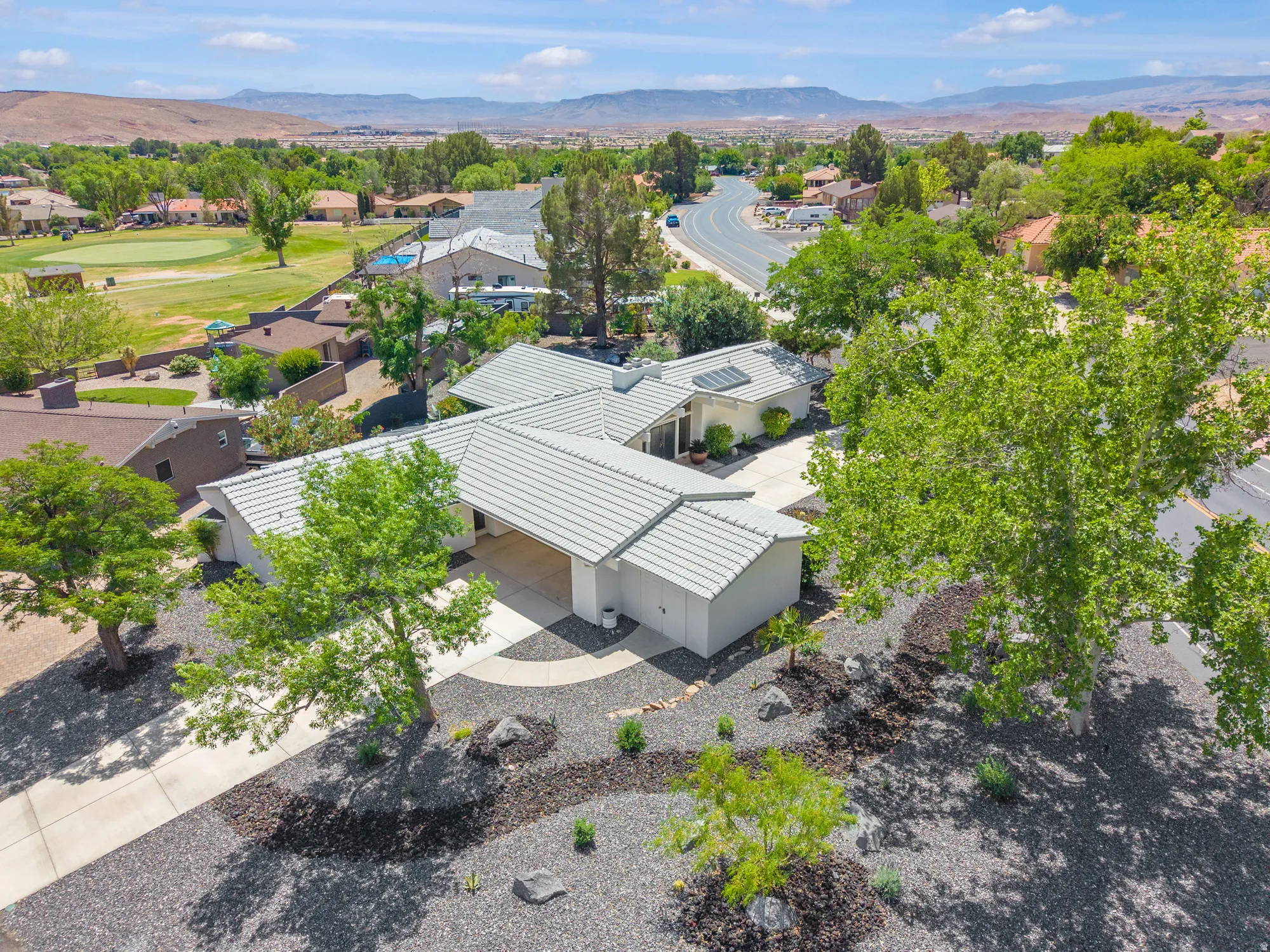 Aerial view of residential area featuring a mountain backdrop and a golf course