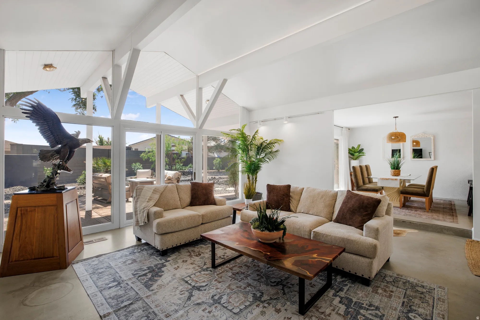 Living area featuring concrete flooring, beam ceiling, and expansive windows