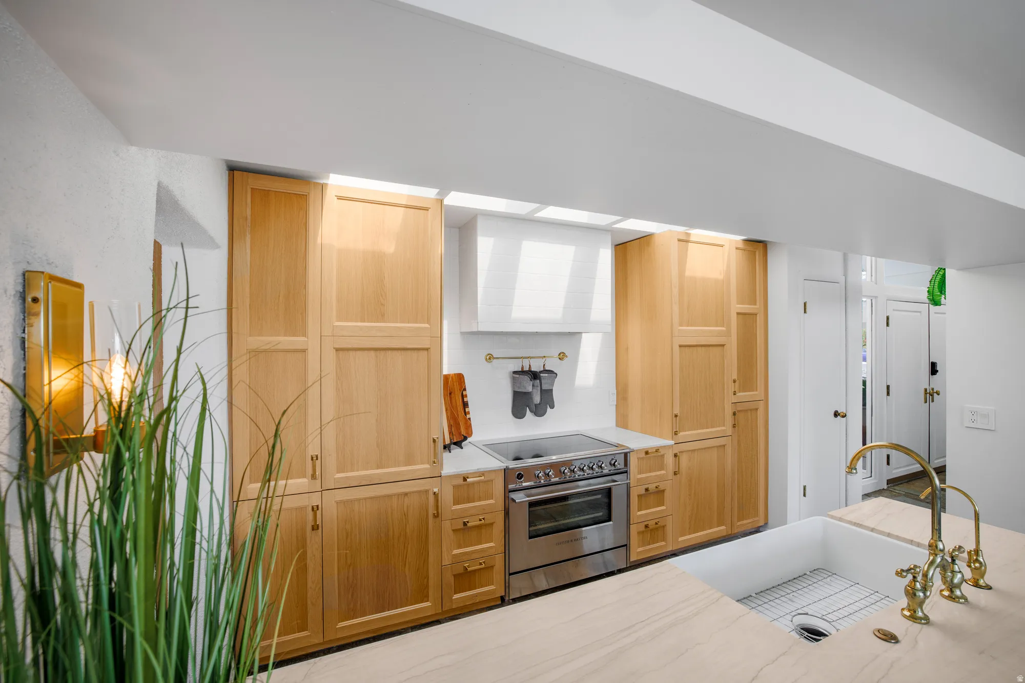 Kitchen with light wood finish cabinetry, tasteful backsplash, and electric stovetop