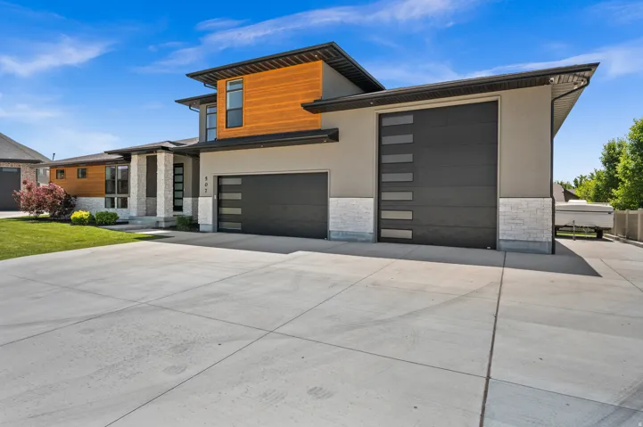 Modern home featuring stone siding, driveway, a garage, and stucco siding