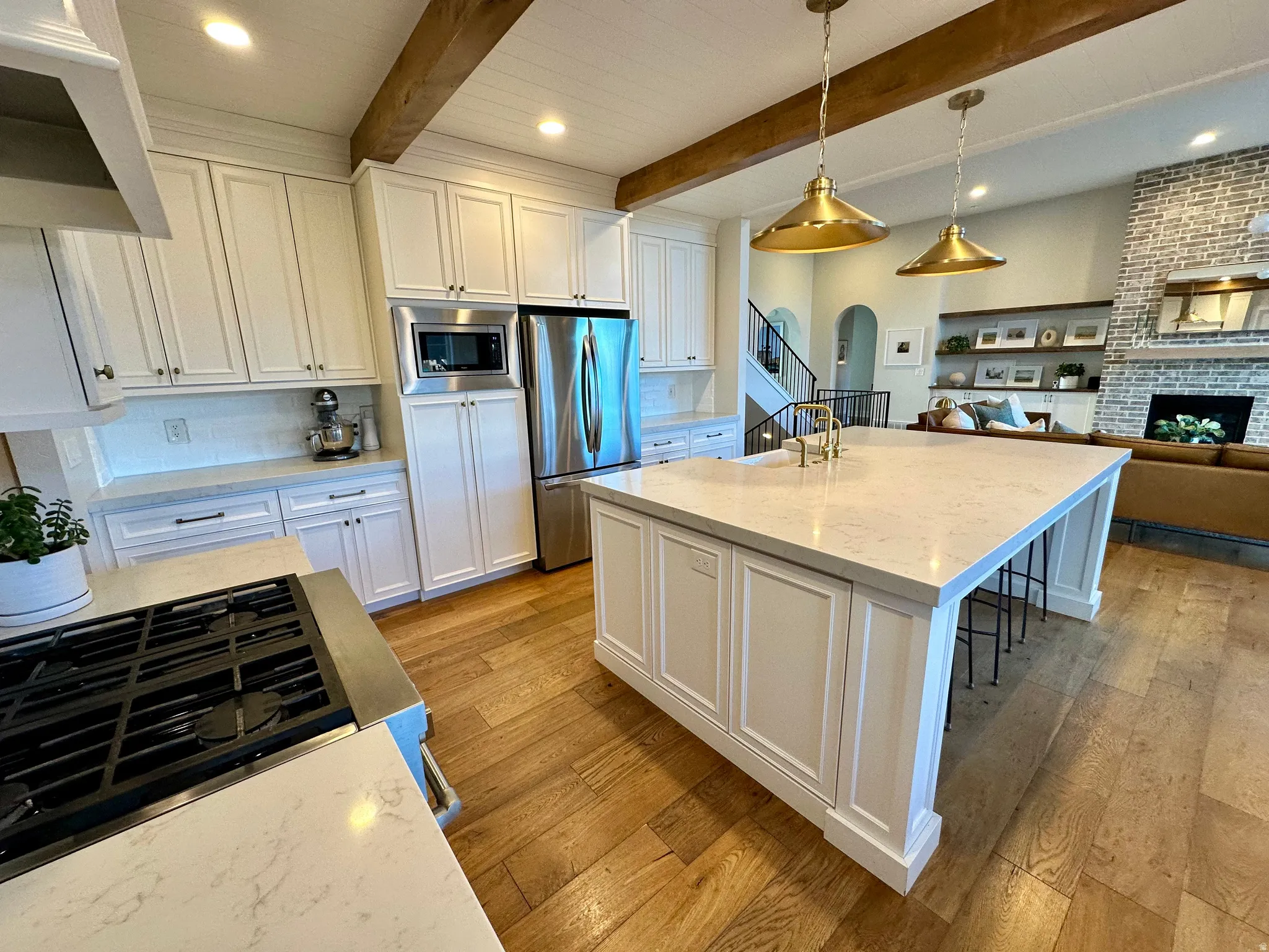 Kitchen with white cabinets, light stone counters, open floor plan, light wood-style flooring, and stainless steel appliances