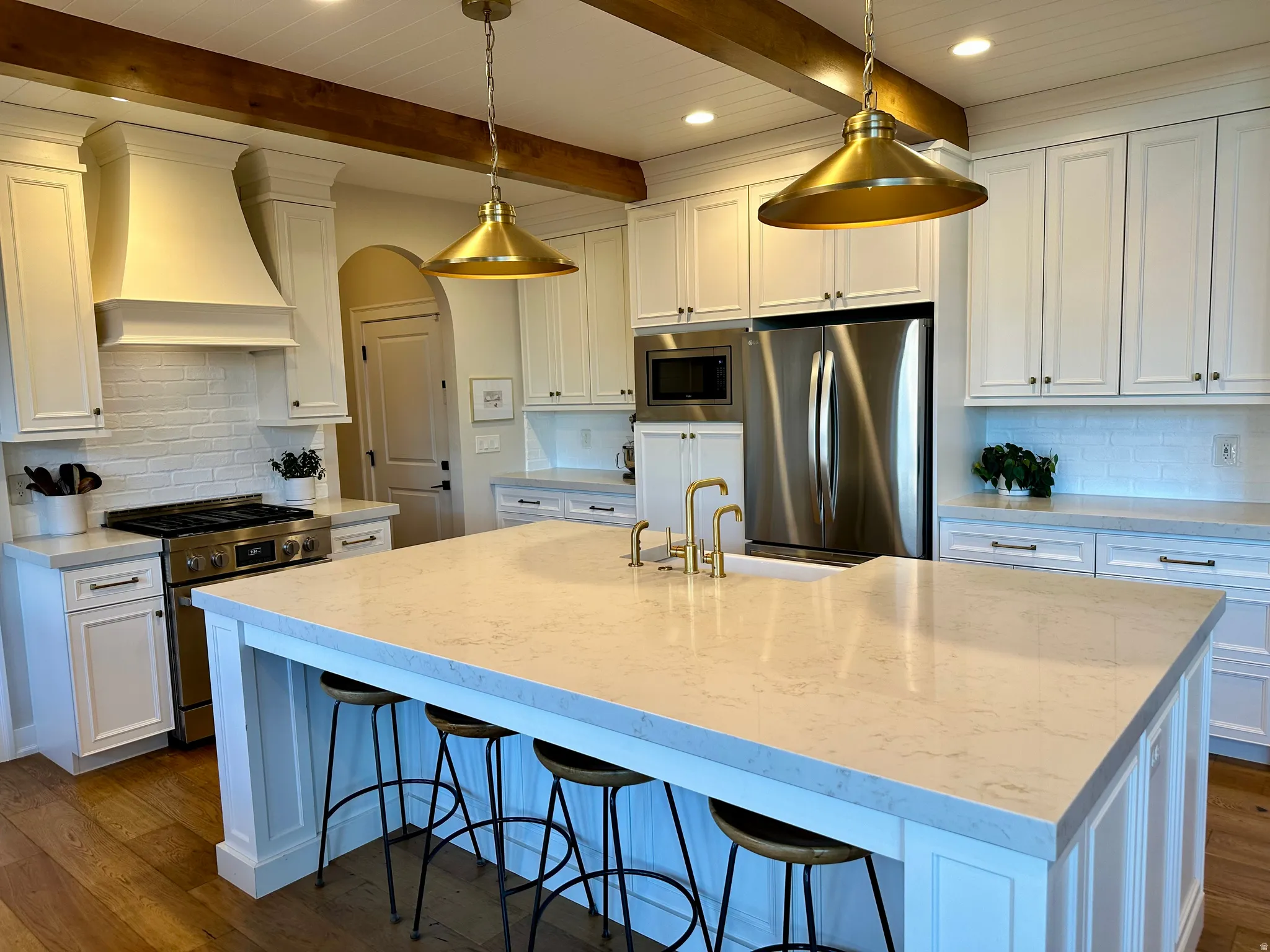 Kitchen with backsplash, white cabinets, dark wood-type flooring, a kitchen bar, and beamed ceiling