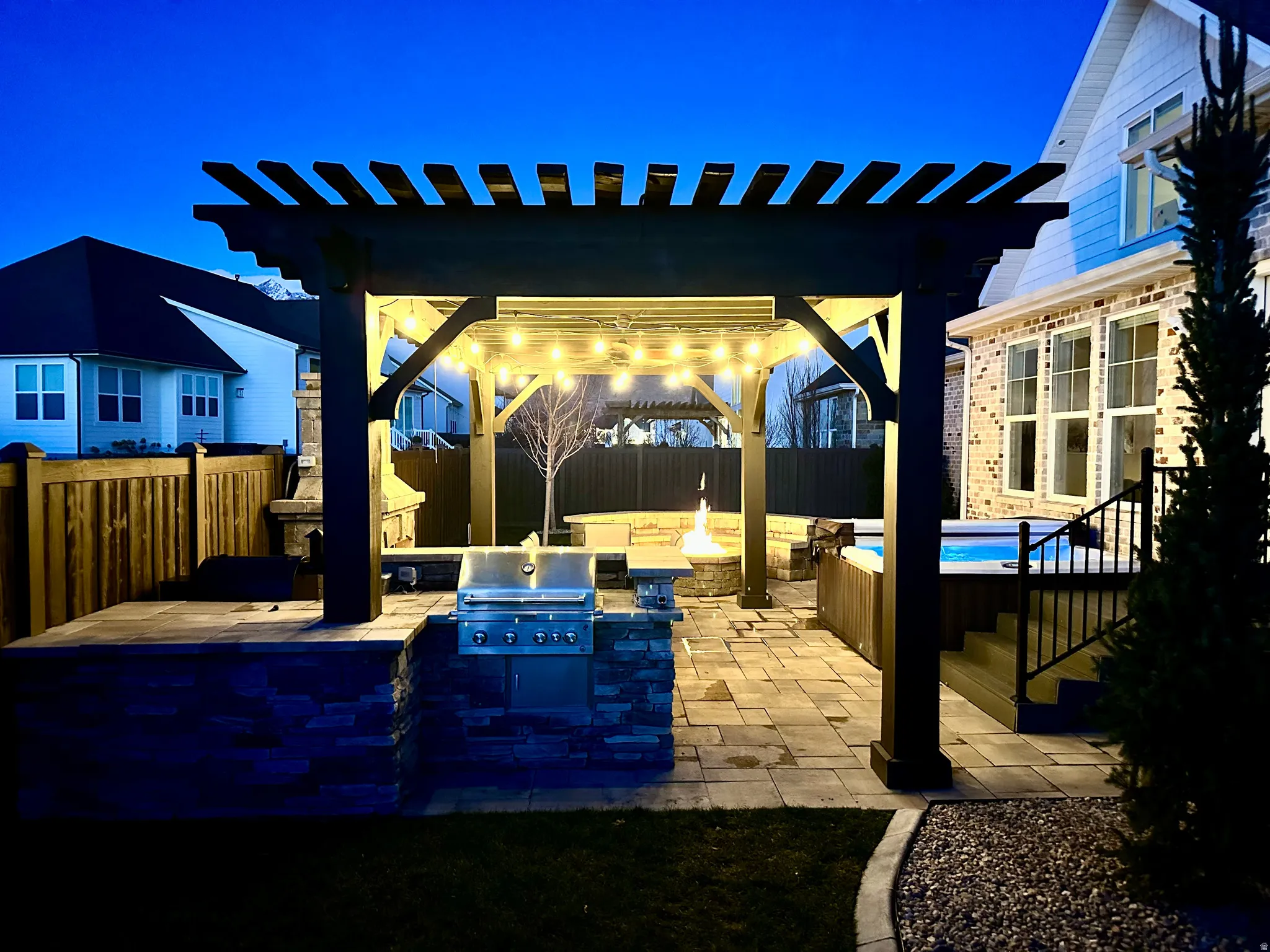 Fenced backyard with a pergola, Hot Tub, BBQ, a patio, an outdoor fire pit, and exterior kitchen