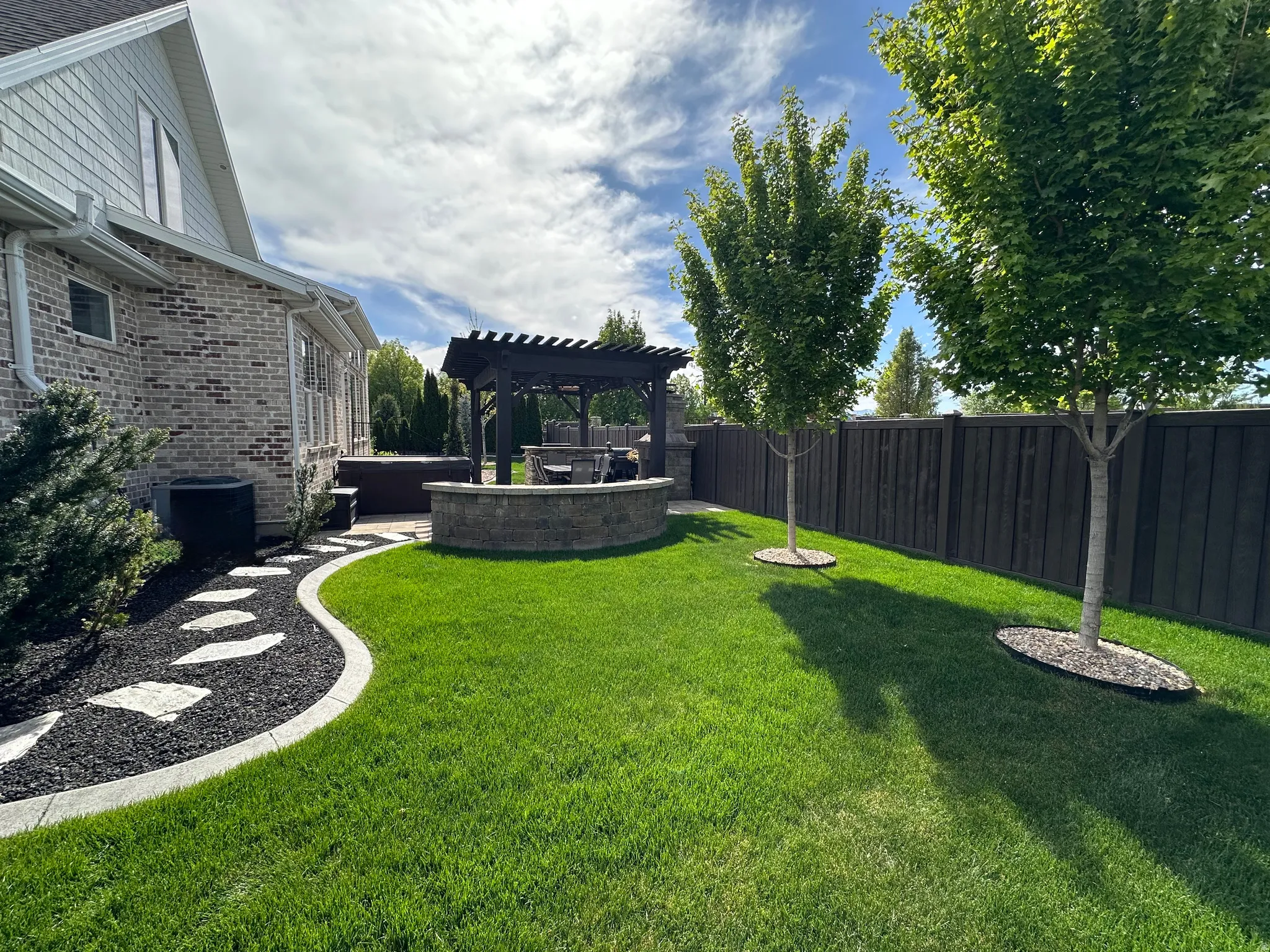 Fenced backyard featuring a pergola, a patio area, and a jacuzzi