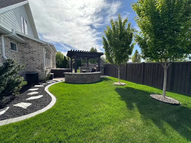 Fenced backyard featuring a pergola, a patio area, and a jacuzzi