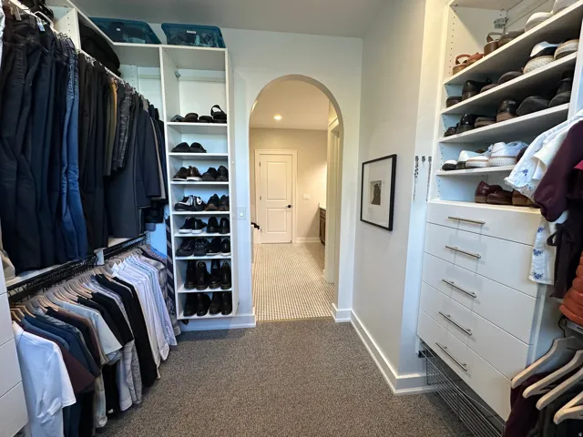 Master Walk in closet featuring arched walkways and dark carpet