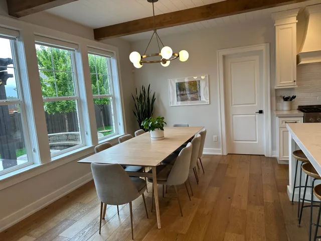 Dining area with dark wood-type flooring, suspended lighting, and beamed ceiling