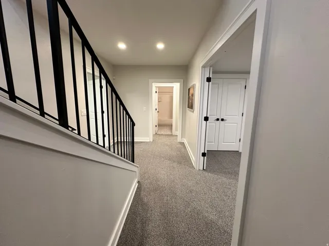 Hallway with light carpet and stairway