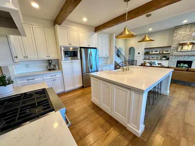 Kitchen with white cabinets, light stone counters, open floor plan, light wood-style flooring, and stainless steel appliances