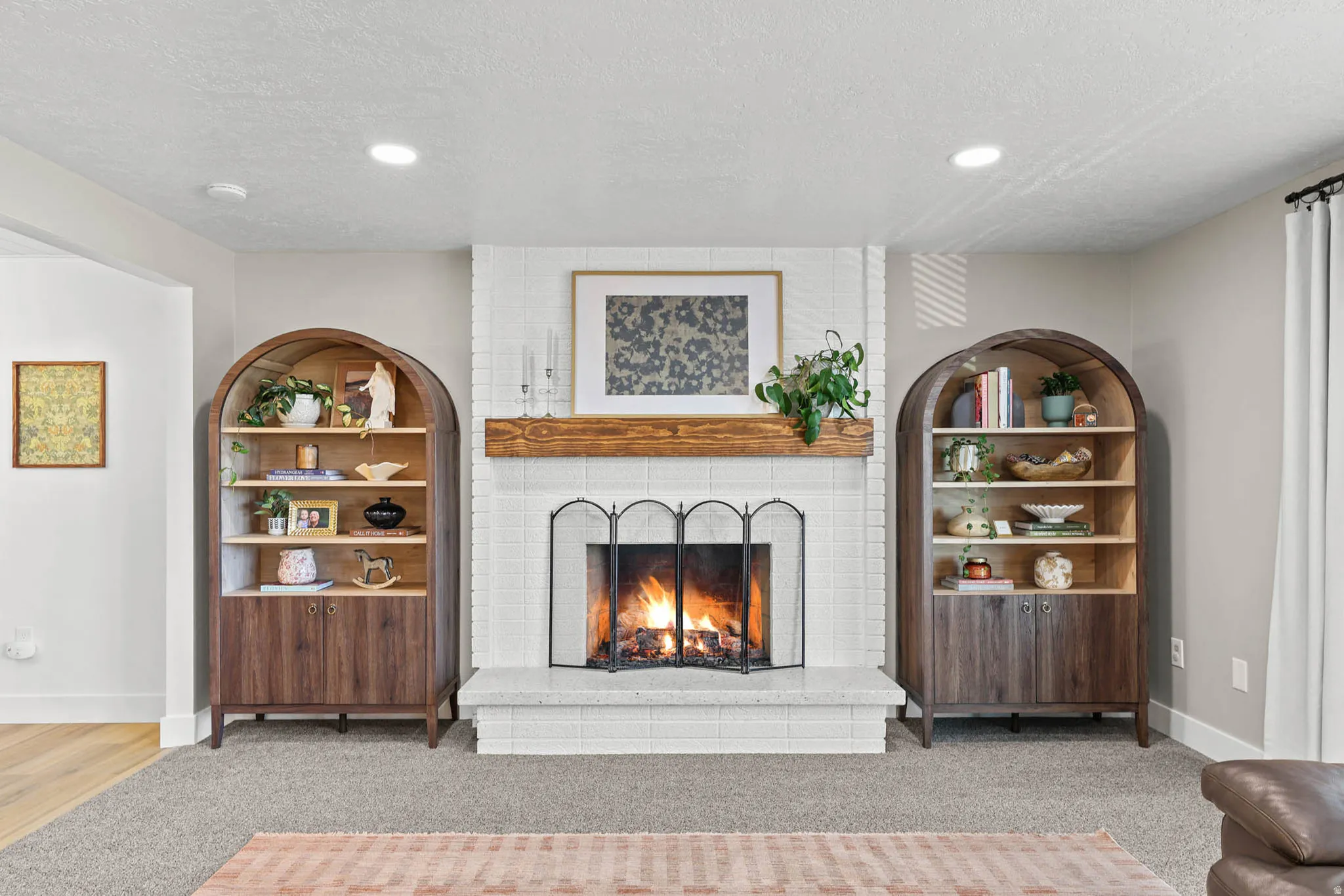 Living area featuring a brick fireplace, light carpet, a textured ceiling, and recessed lighting