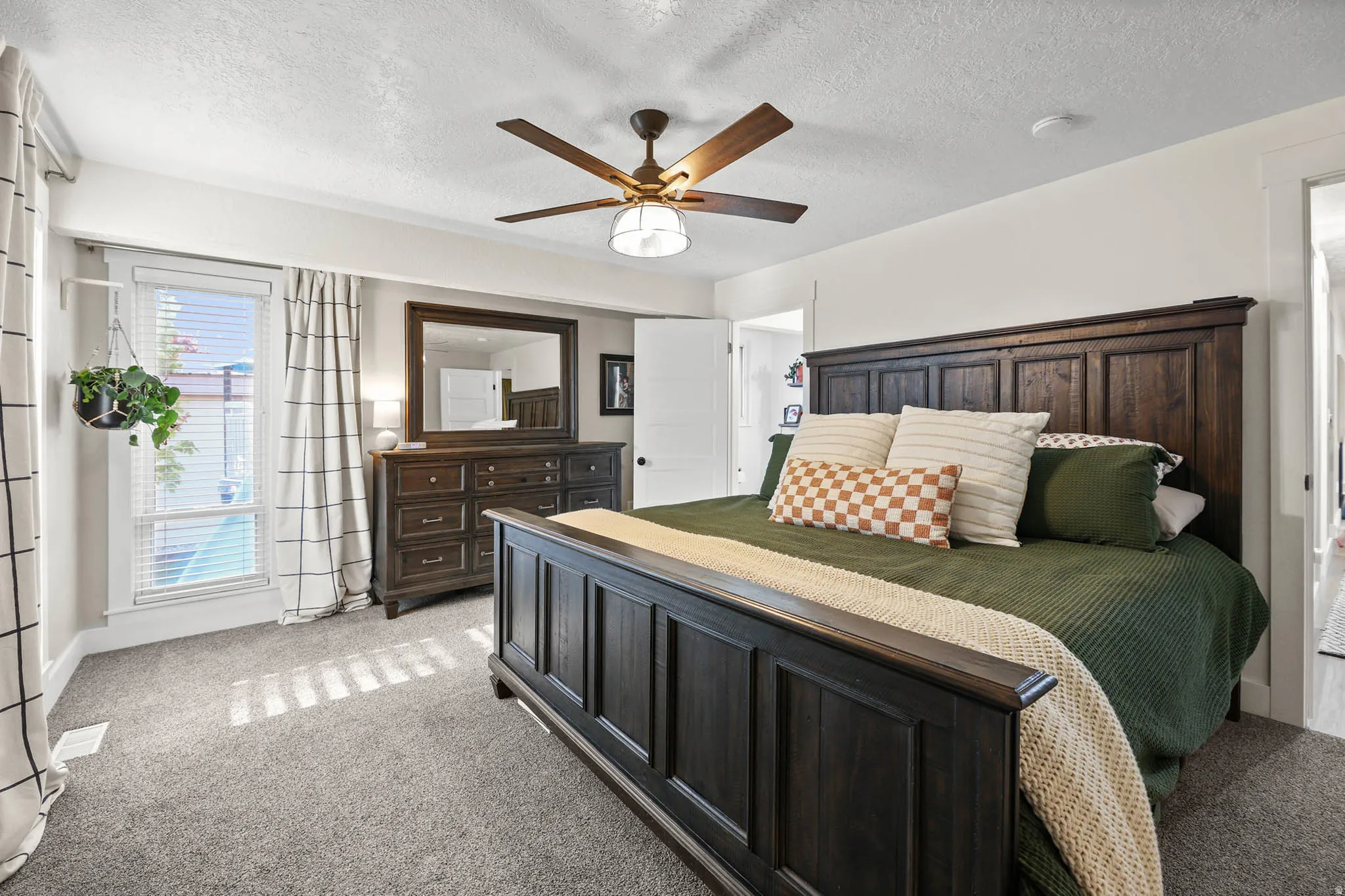 Carpeted bedroom with a textured ceiling and ceiling fan