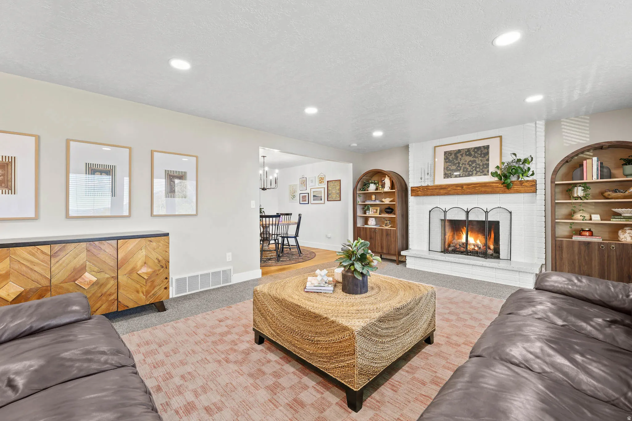 Living room featuring carpet, a textured ceiling, a fireplace, built in shelves, and recessed lighting