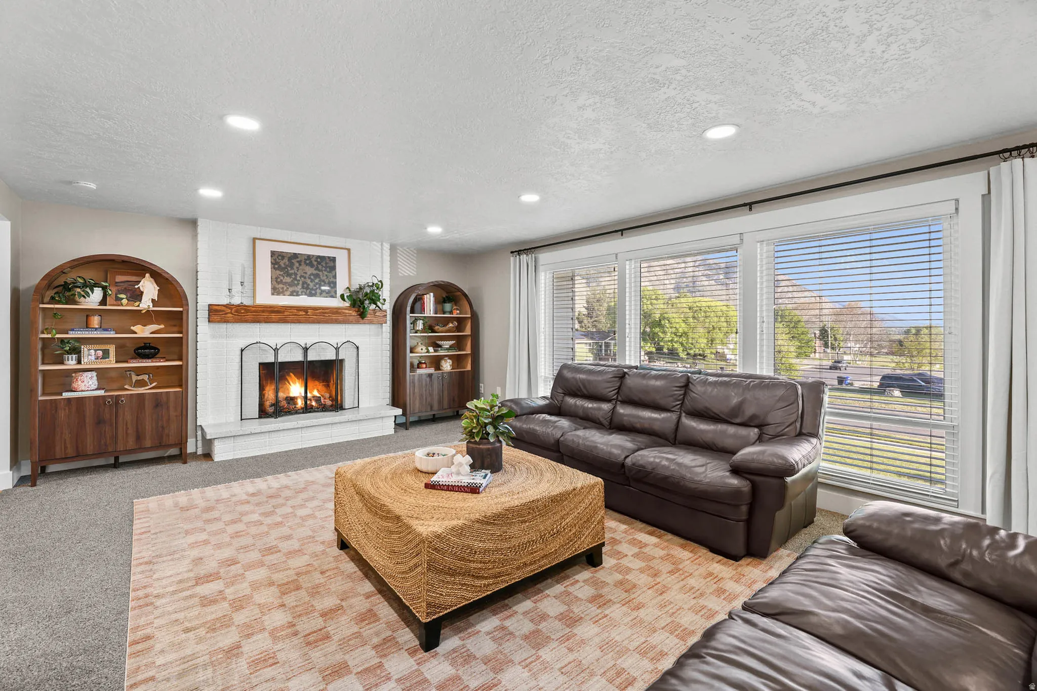 Living area with a textured ceiling, carpet floors, recessed lighting, a brick fireplace, and built in features