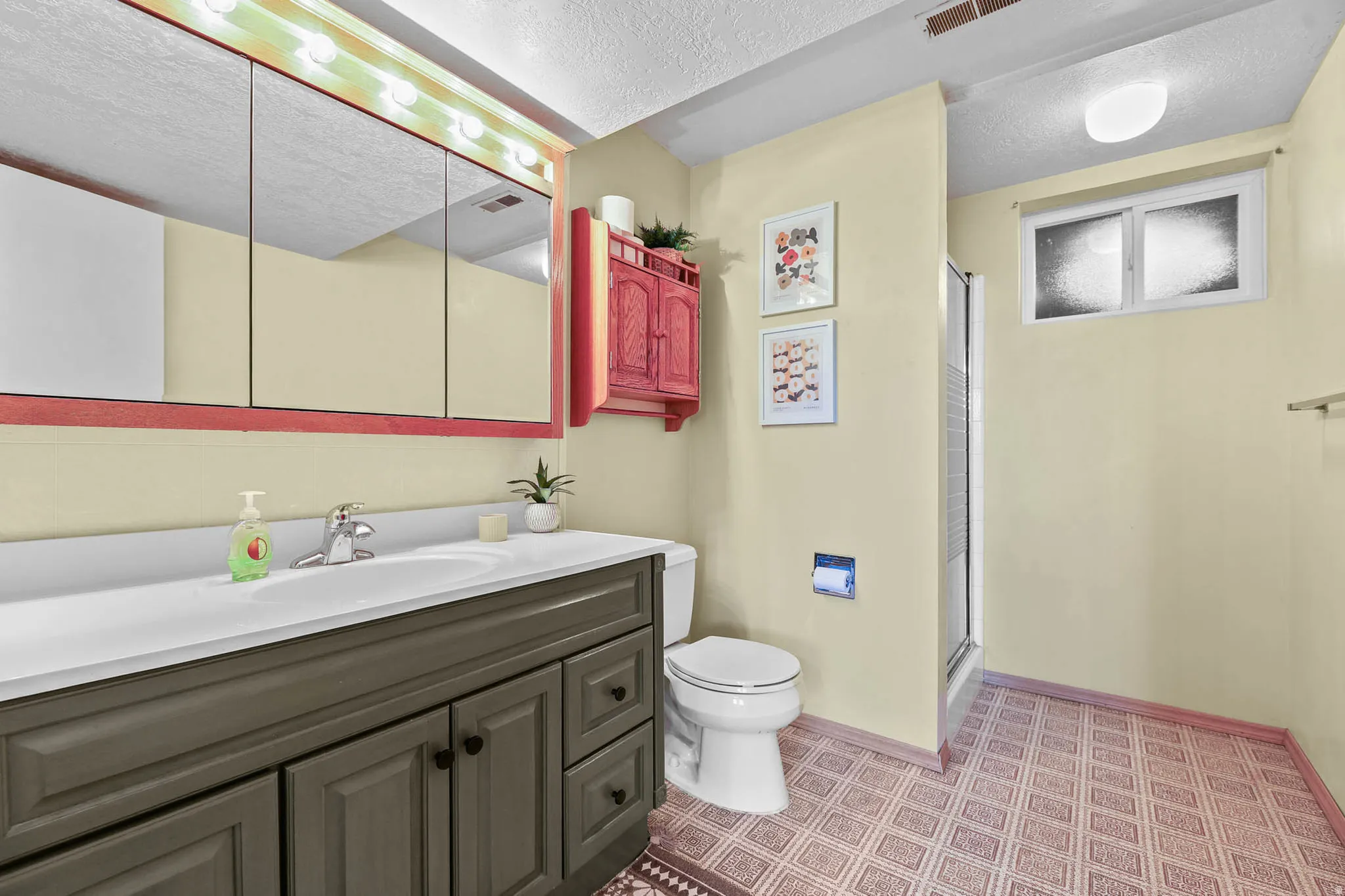 Bathroom featuring a textured ceiling, a shower stall, and vanity