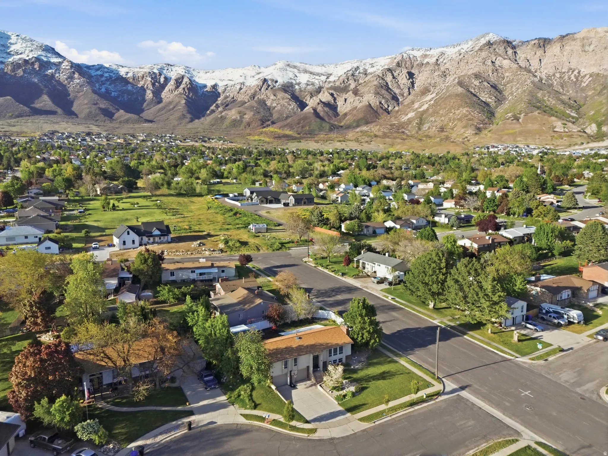 Aerial view of property and surrounding area featuring a mountainous background and nearby suburban area