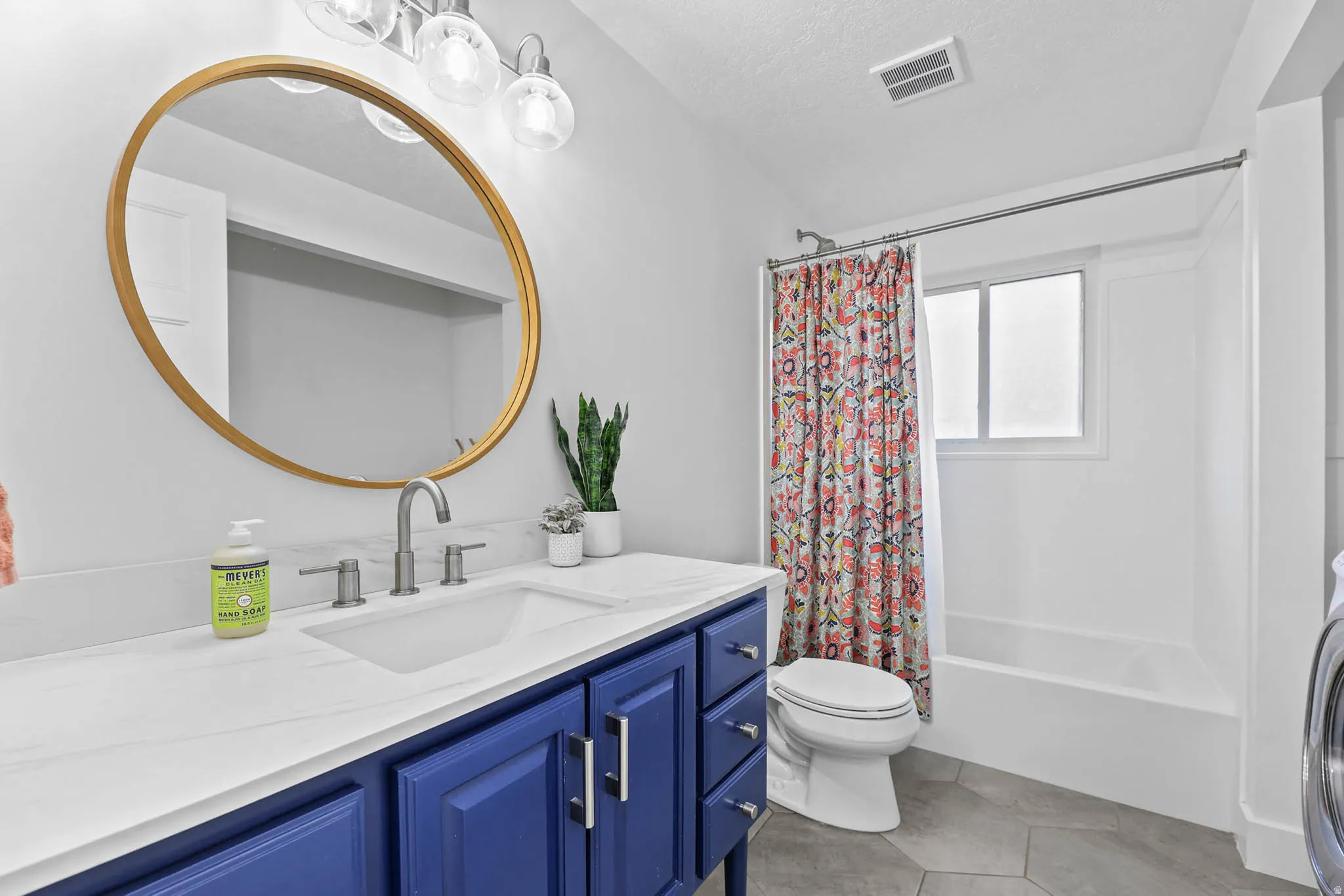 Bathroom with vanity, shower / bath combo with shower curtain, and a textured ceiling
