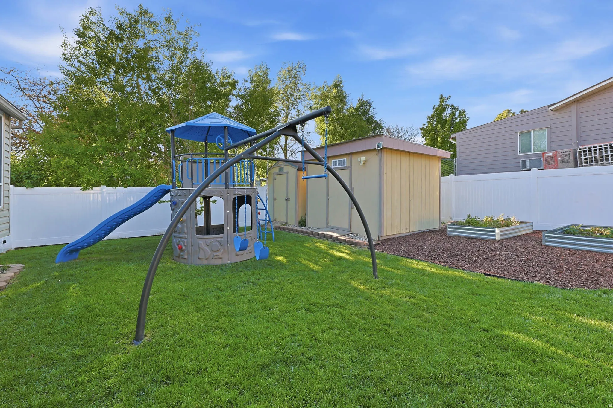 View of play area featuring a garden, a fenced backyard, and a shed