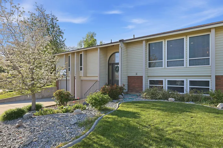 Raised ranch with a front lawn, an attached garage, and driveway