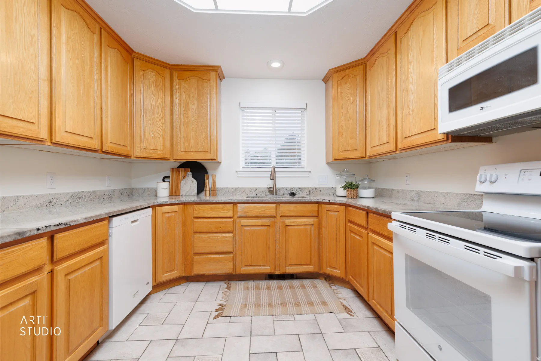 Kitchen with white appliances, light stone countertops, and recessed lighting